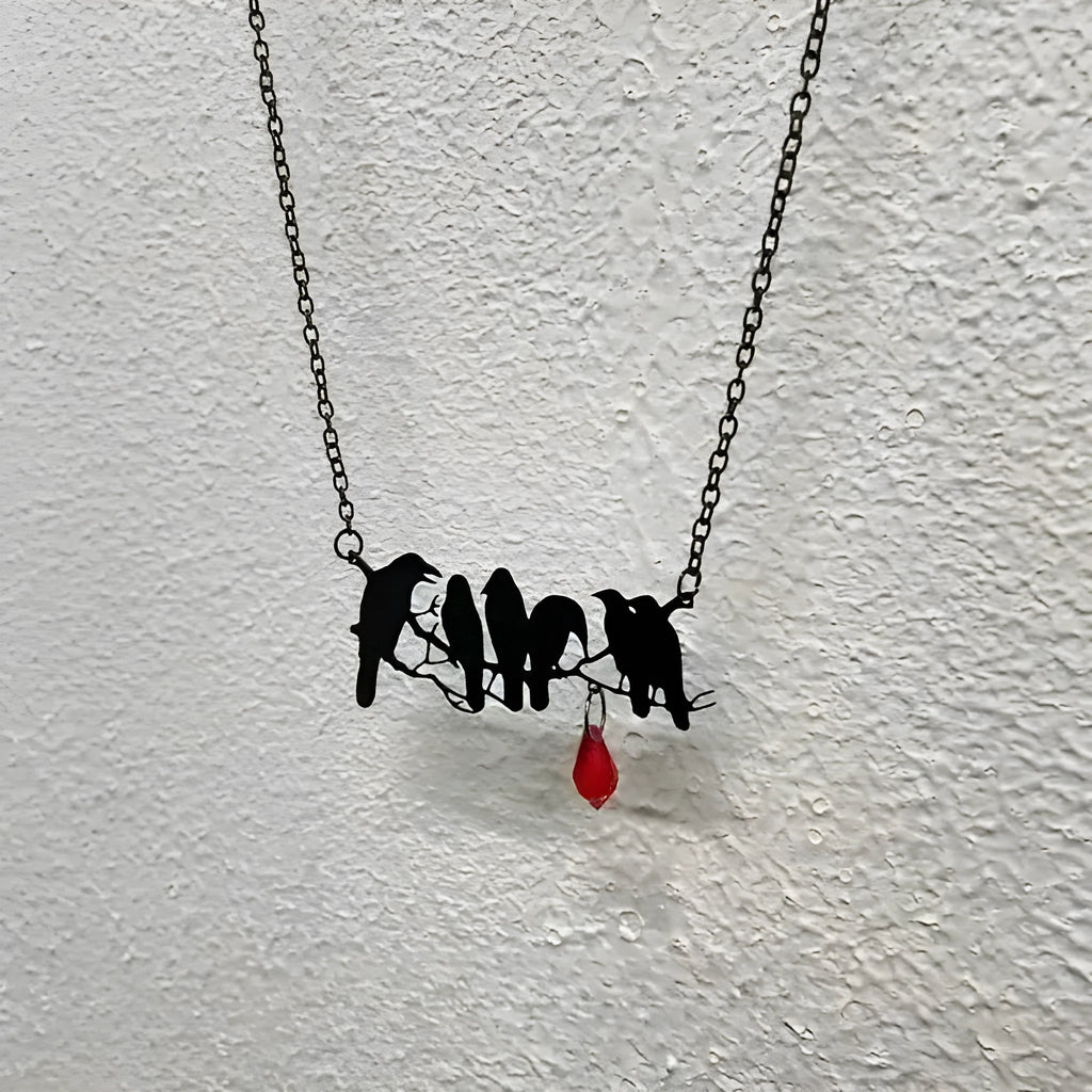 Black crow pendant necklace with cross chain on dark background