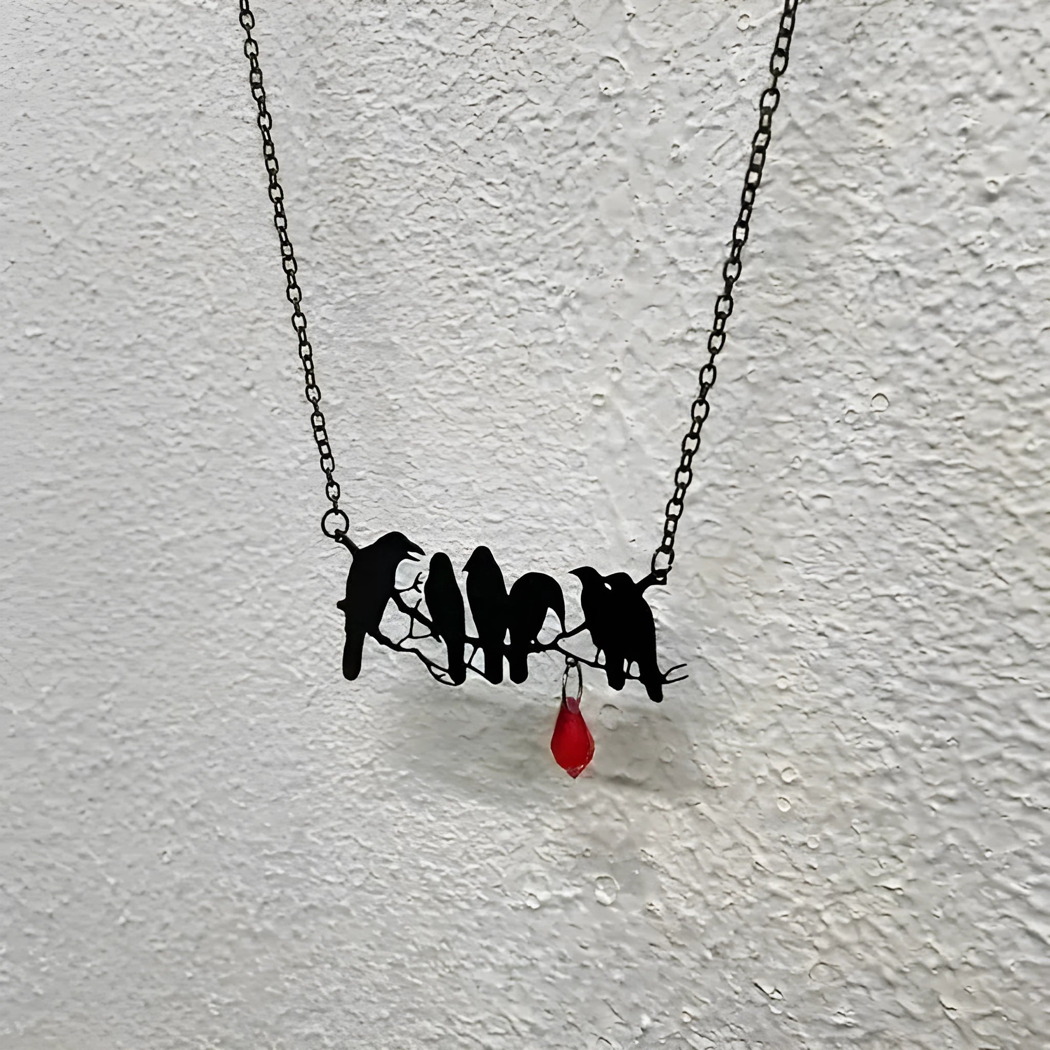 Black crow pendant necklace with cross chain on dark background