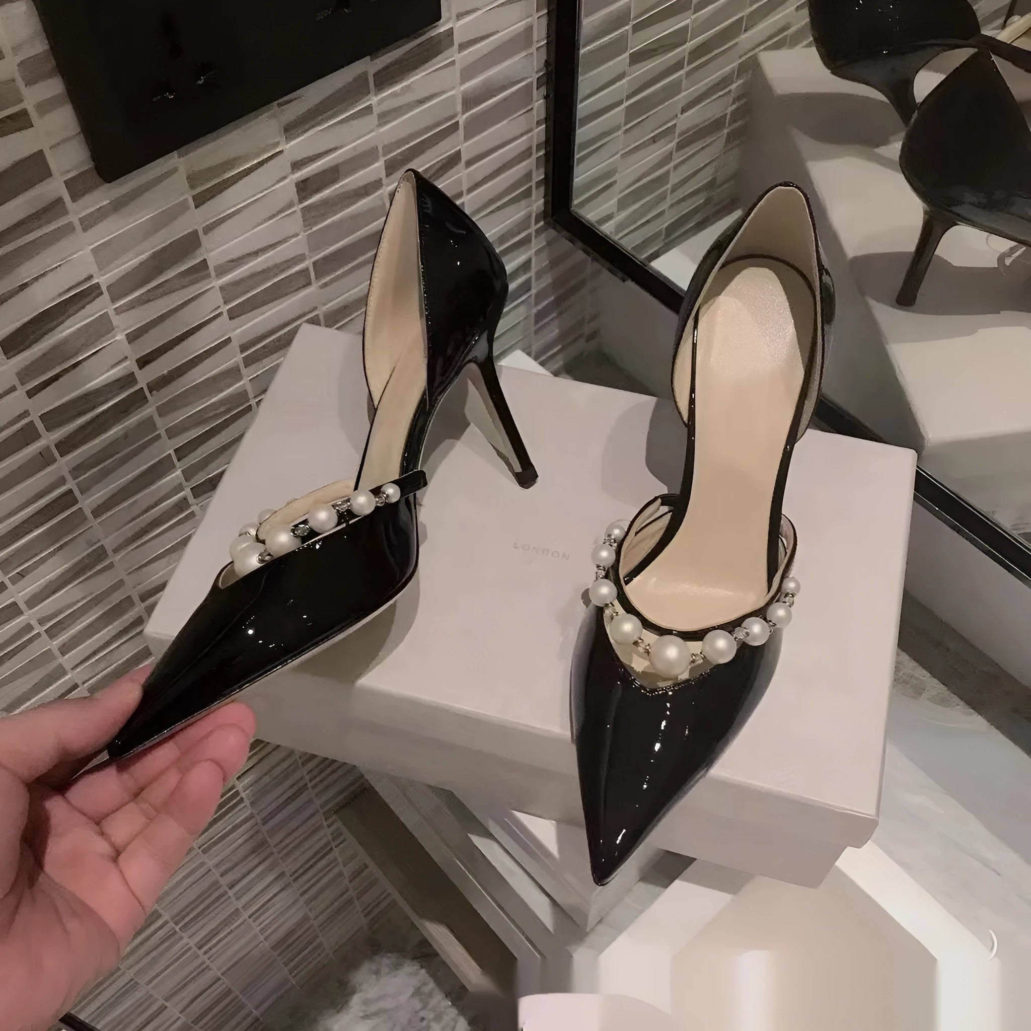 Women's pointed toe patent leather stiletto high heels with pearl decoration on the upper.