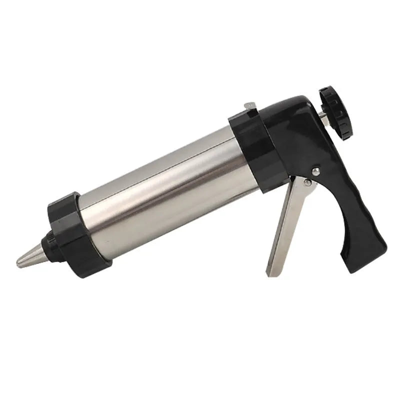 Stainless steel biscuit press gun with assorted cookie moulds and piping nozzles on a baking tray.