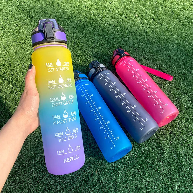 Blue Tritan water bottle with time markers, flip-top lid, and wrist strap on a gym bag