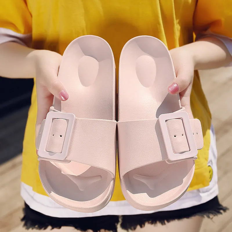 Women's grey blue buckle flip-flop slippers on a light background, showing adjustable strap and cushioned sole.