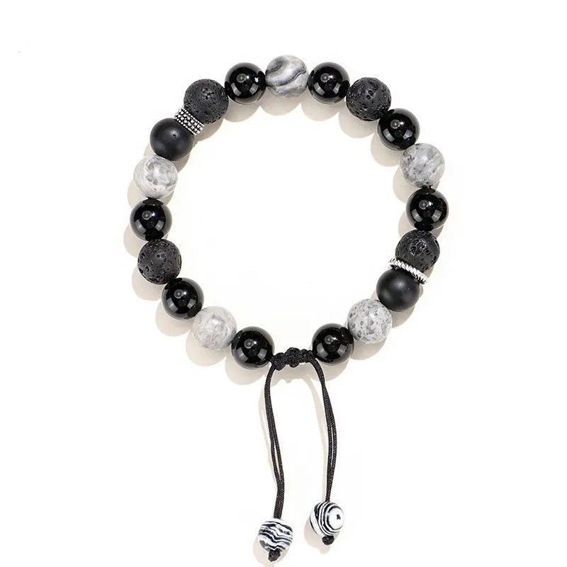 Black agate map stone volcanic rock bracelet with diamond-shaped beads on a wrist.