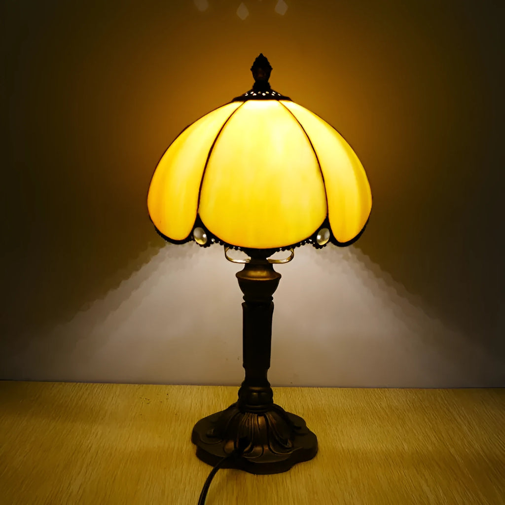 Beige fabric bedside lamp with 20cm wide shade on a table.