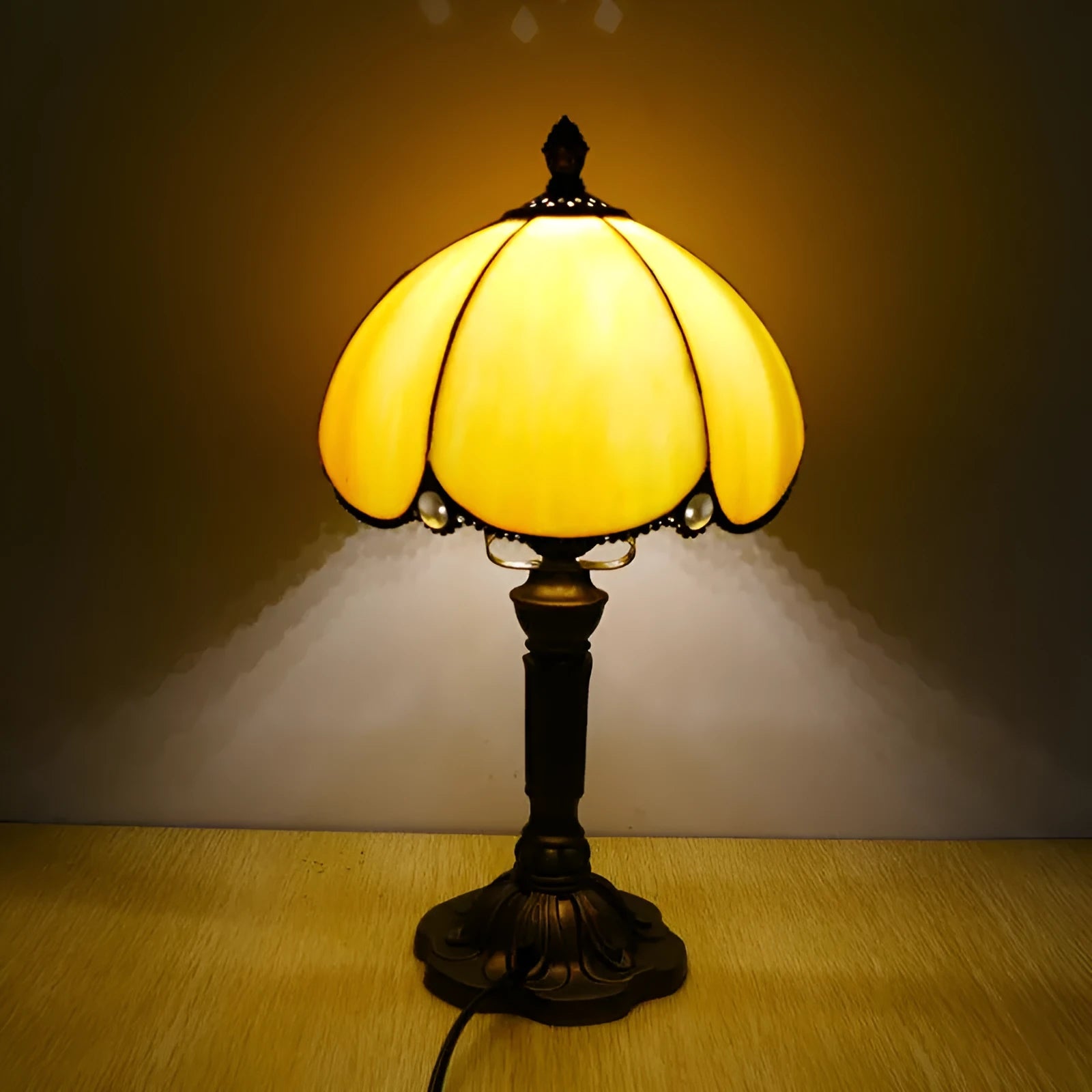 Beige fabric bedside lamp with 20cm wide shade on a table.