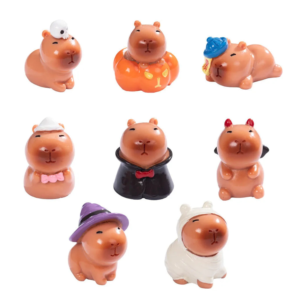 Set of eight small Halloween-themed capybara resin figurines on a wooden surface.