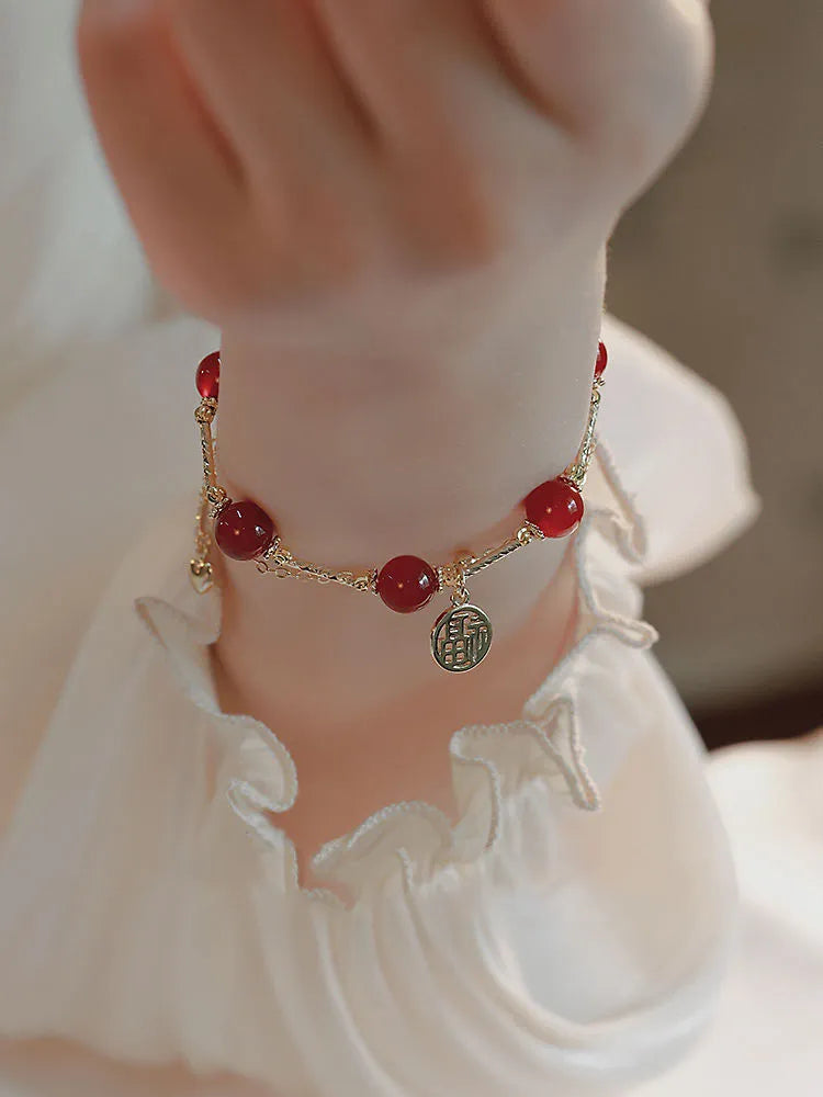 Close-up of a double-layer women's bracelet with a red agate blessing card and a red horse charm on an alloy band.