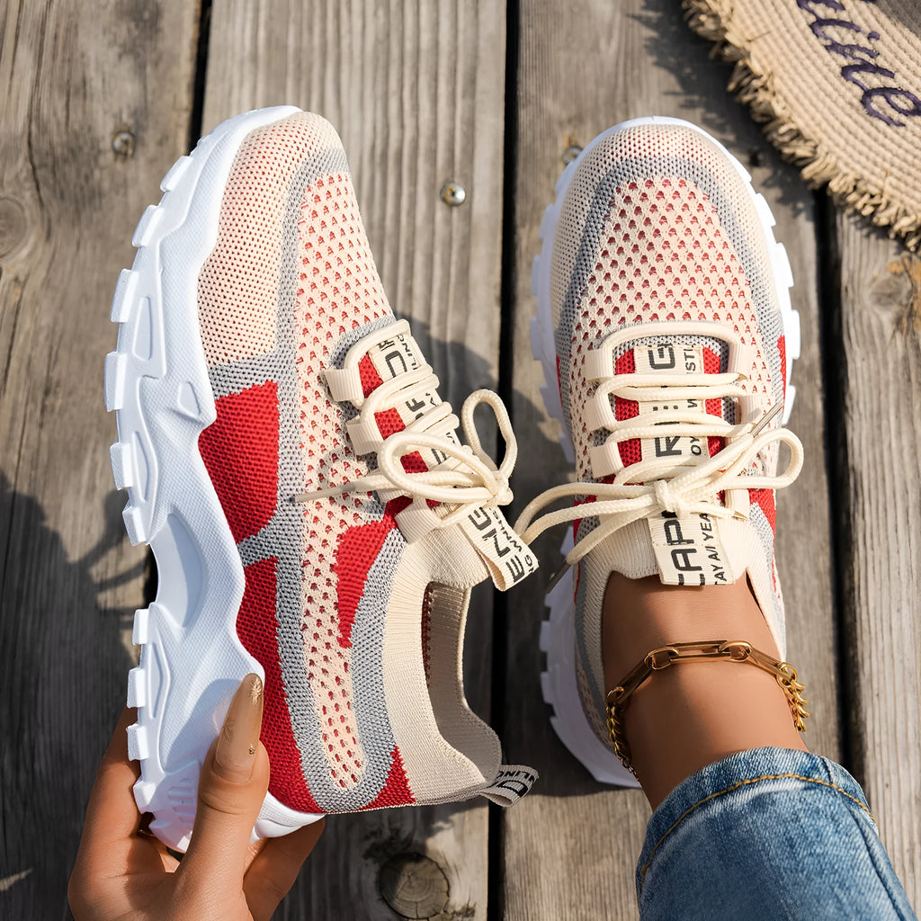 Women's Flyknit mesh sneakers in grey and white, showcasing the breathable upper and flat rubber sole.