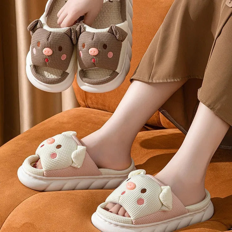 Pair of piggy cute open toe linen flip flop slippers for couples on a plain background.