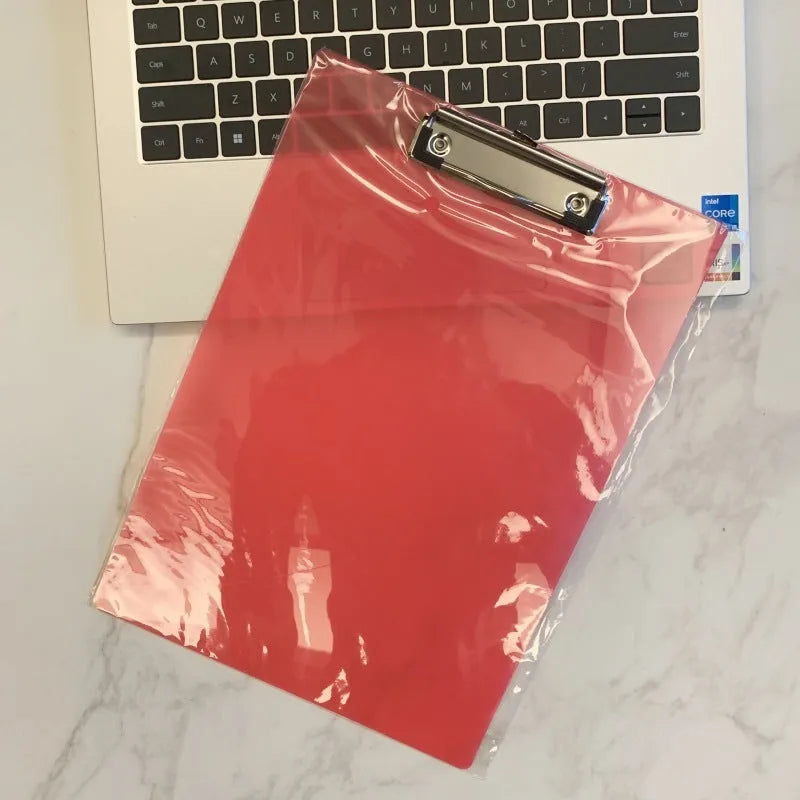 Clear A4 plate holder with metal clip and transparent writing pad in blue colour on a desk.