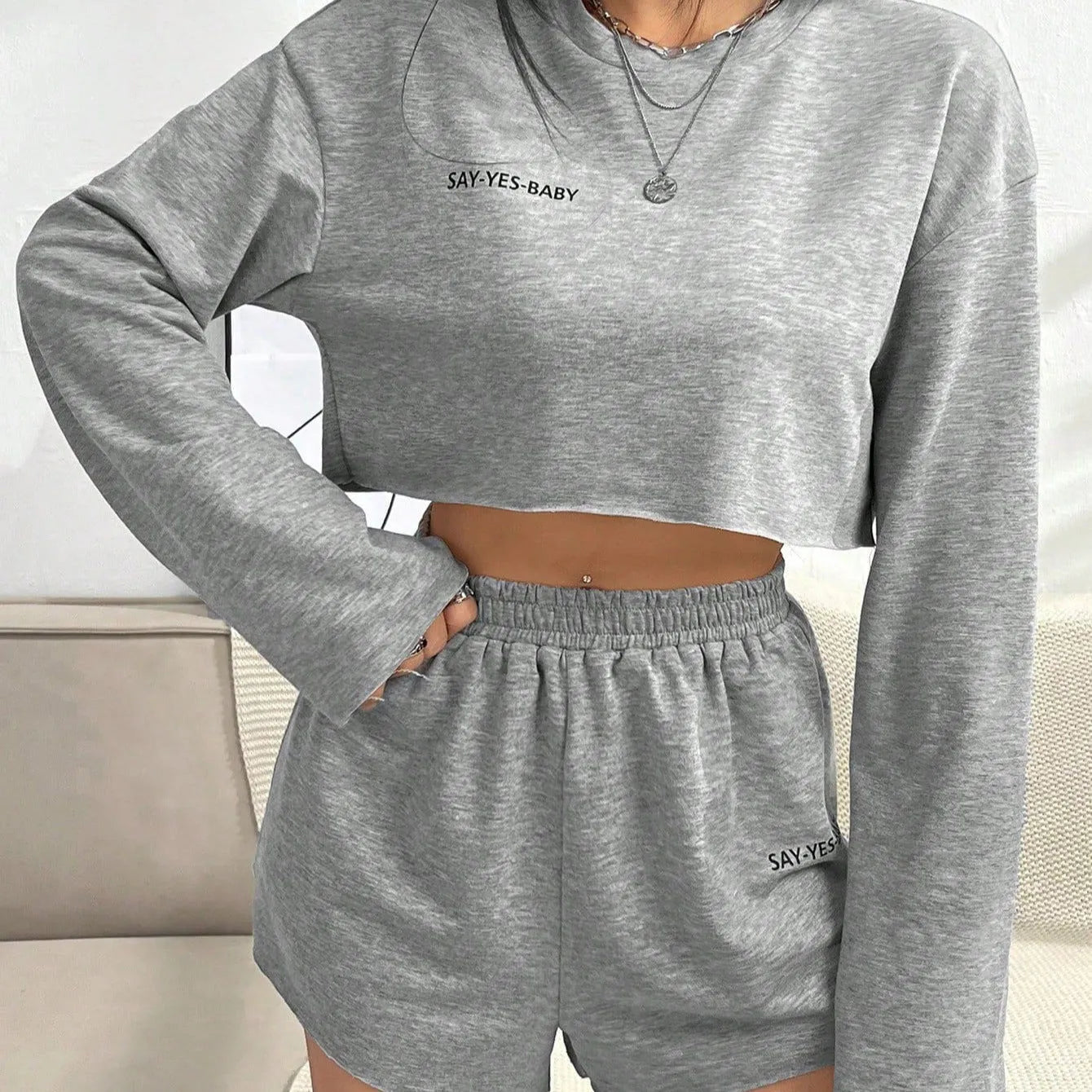 Grey women's long-sleeved polyester top and shorts casual suit set laid flat.