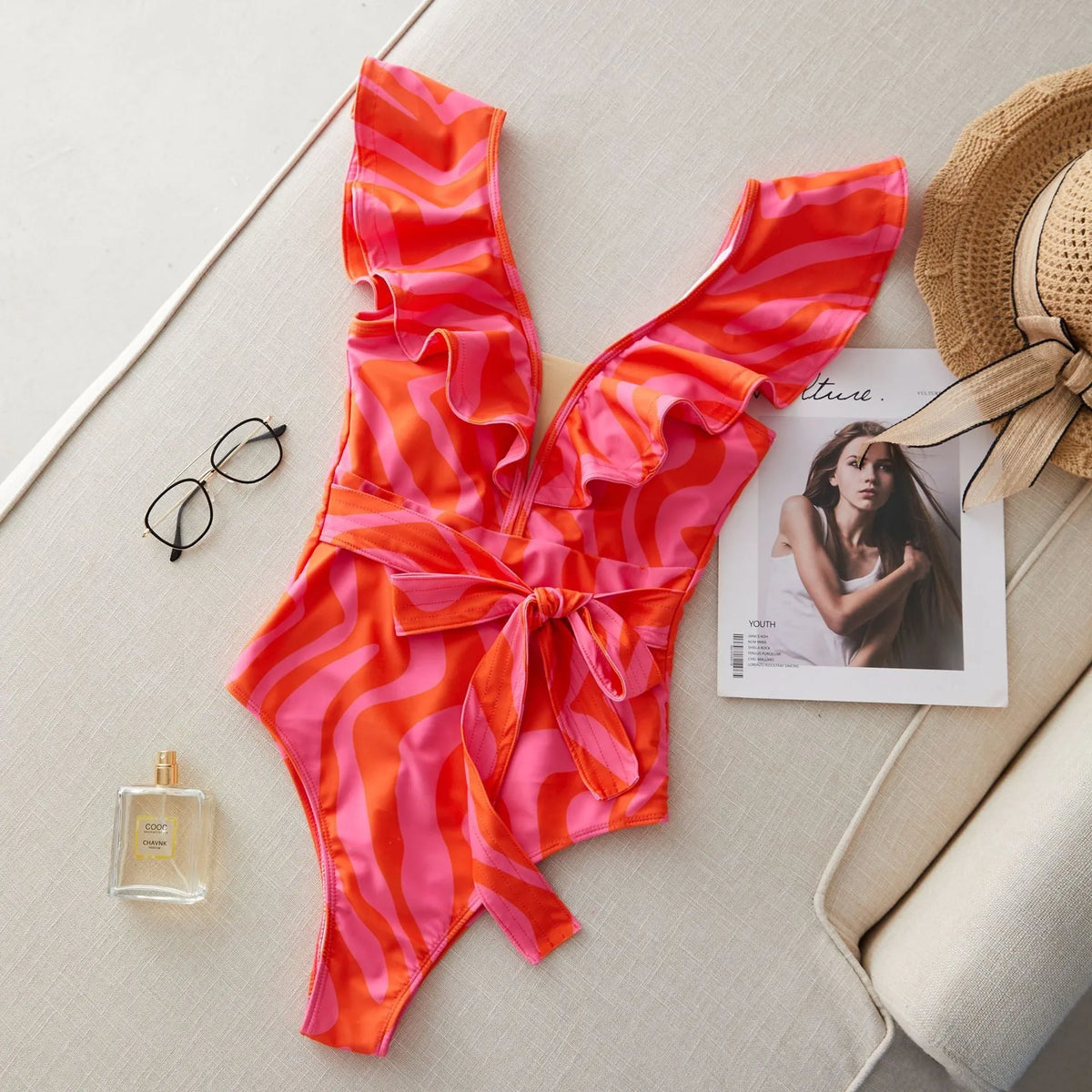 Women's deep V-neck one-piece swimsuit with mesh stitching and ruffled shoulders in a printing pattern.