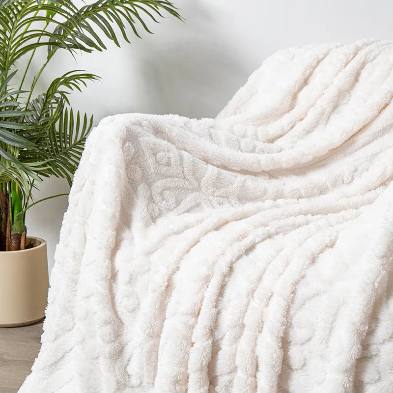 Shu cotton velvet jacquard blanket in fog blue with a plant flower pattern, laid over a grey sofa.