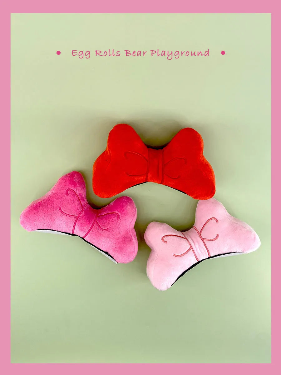 Plush bow tie helmet decoration measuring 15cm in bright red, peach pink, and rose pink colour options