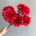 A fan-shaped display of silk dahlia, peony and rose flowers in a yellow colour on a wooden desktop.