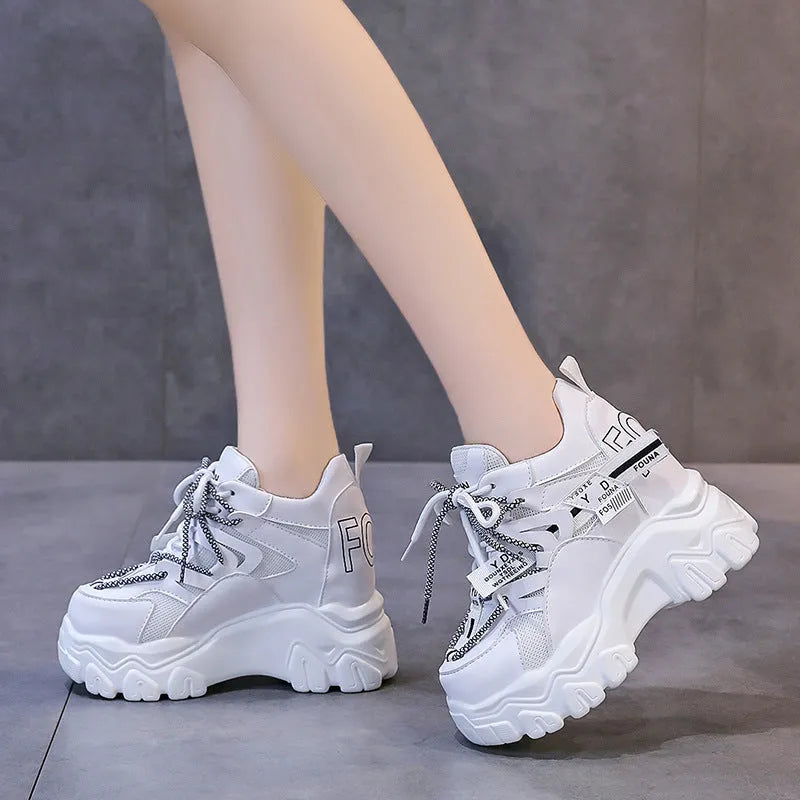 Women's white low-top platform sports shoes with cross strap and rubber sole on a light background
