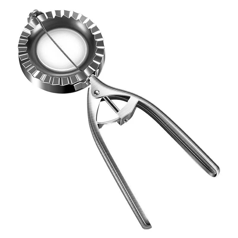 Silver stainless steel manual dumpling press mould with handle on a kitchen worktop.