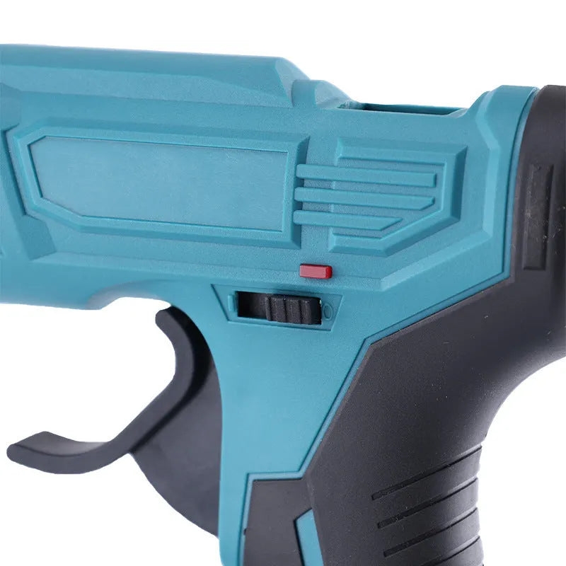 Cordless hot glue gun with two batteries, a charger, and a pack of glue sticks on a workbench.