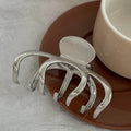 Assortment of silver metal hair claw barrettes in various shapes including waves, bows, and crosses.