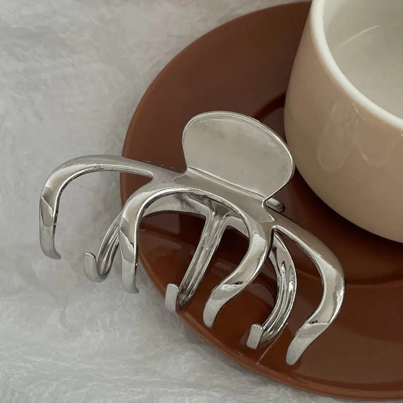 Assortment of silver metal hair claw barrettes in various shapes including waves, bows, and crosses.