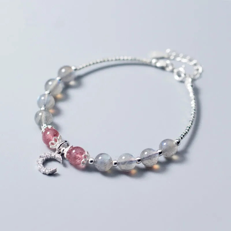 Handmade silver-tone adjustable bracelet with a moonstone bead and small crescent moon charm on a white background.