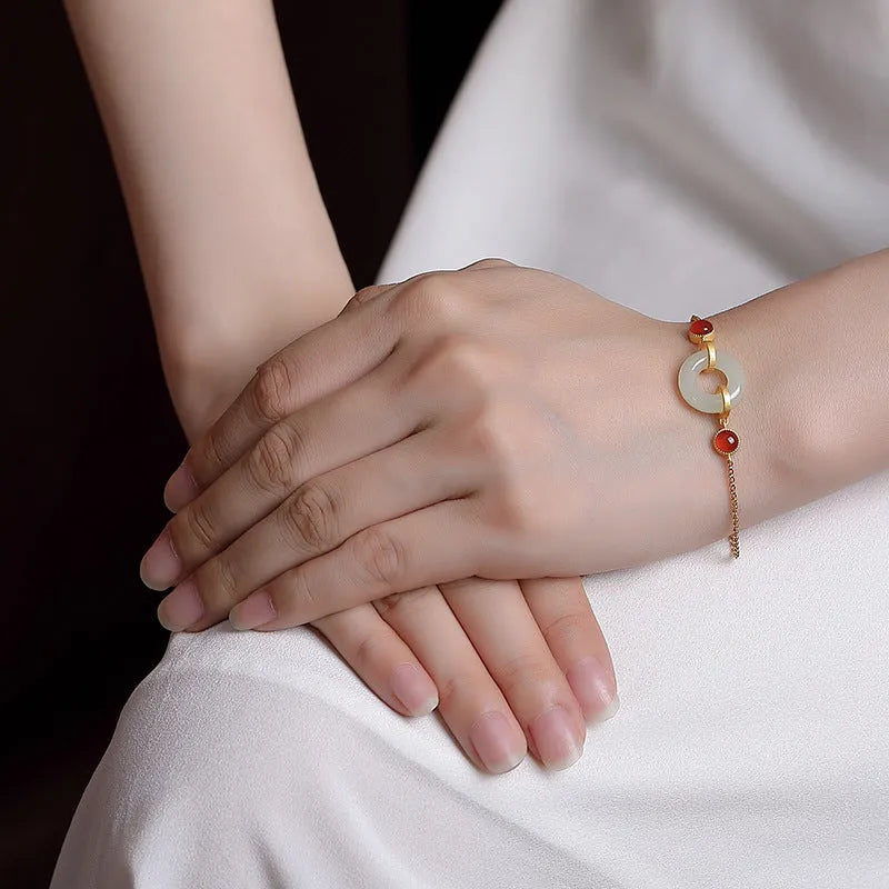 Gold-coloured women's bracelet with a silver base and an inlaid green Hetian jade charm, showing a peace buckle clasp.