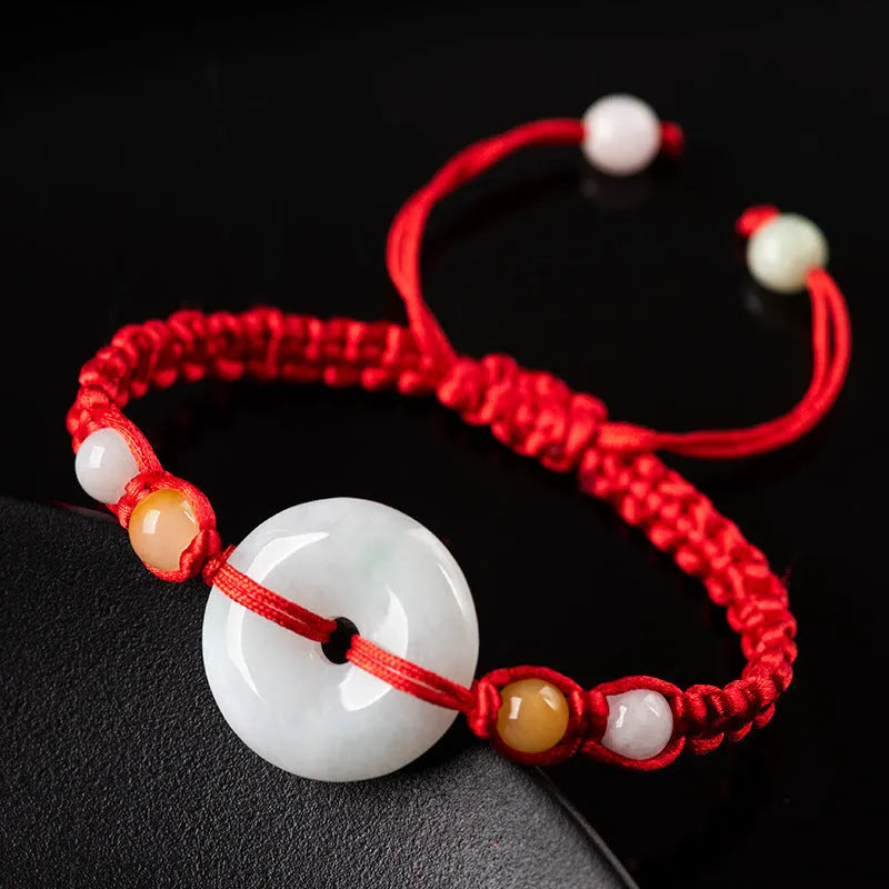 Round emerald green Burma jade pendant on an adjustable red rope bracelet strap.