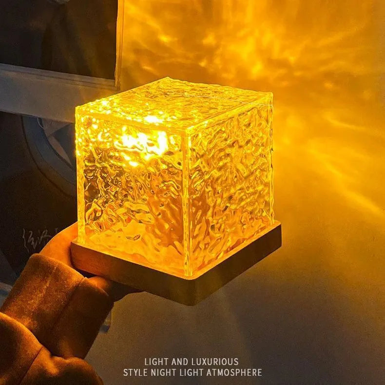 Crystal table lamp projecting blue water ripple light pattern on wall