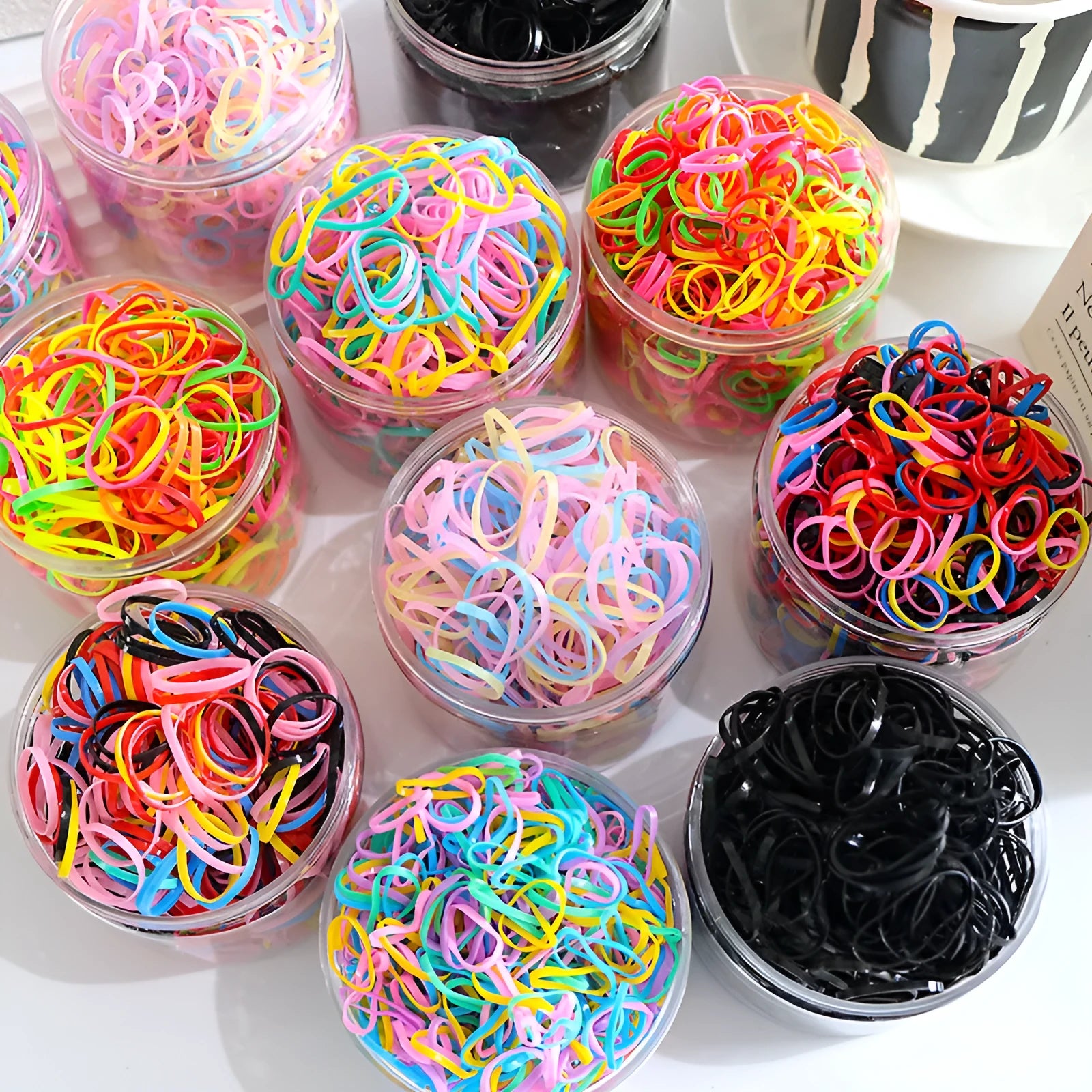 Multicoloured TPU baby hair ties in a reusable plastic container, pack of 300 or 600.