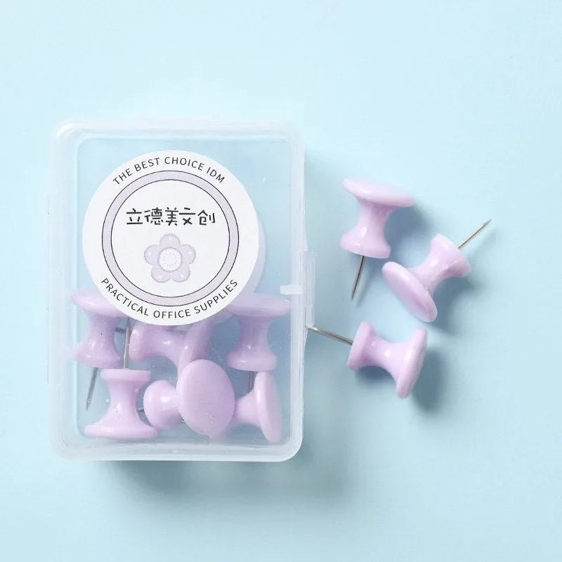 Box of plastic push pins in mint green, pink, and lavender colours, showing large and small thumbtacks for bulletin boards.