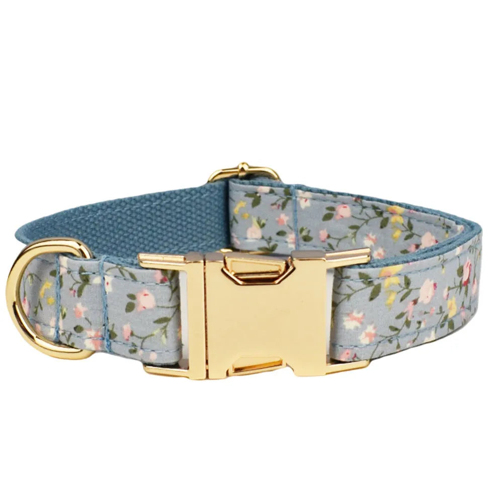 Blue floral pattern dog collar set with matching leash, vest, bow, and poop bag holder on wooden background