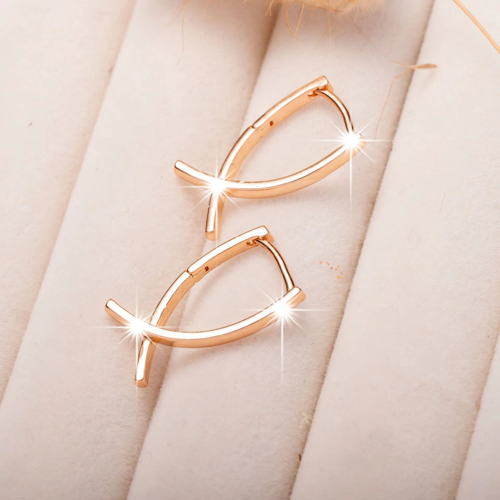 Pair of rose gold cross-shaped earrings on a plain background, showing pierced post design.