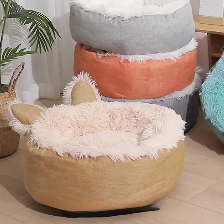 A round soft grey faux fur plush pet bed for cats or small dogs on a wooden floor.