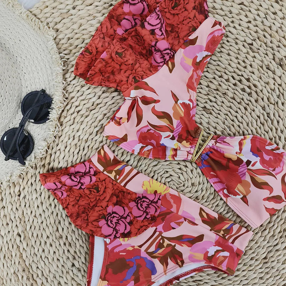 Pink women's one-shoulder ruffled bikini with red flower print and high-waist briefs.