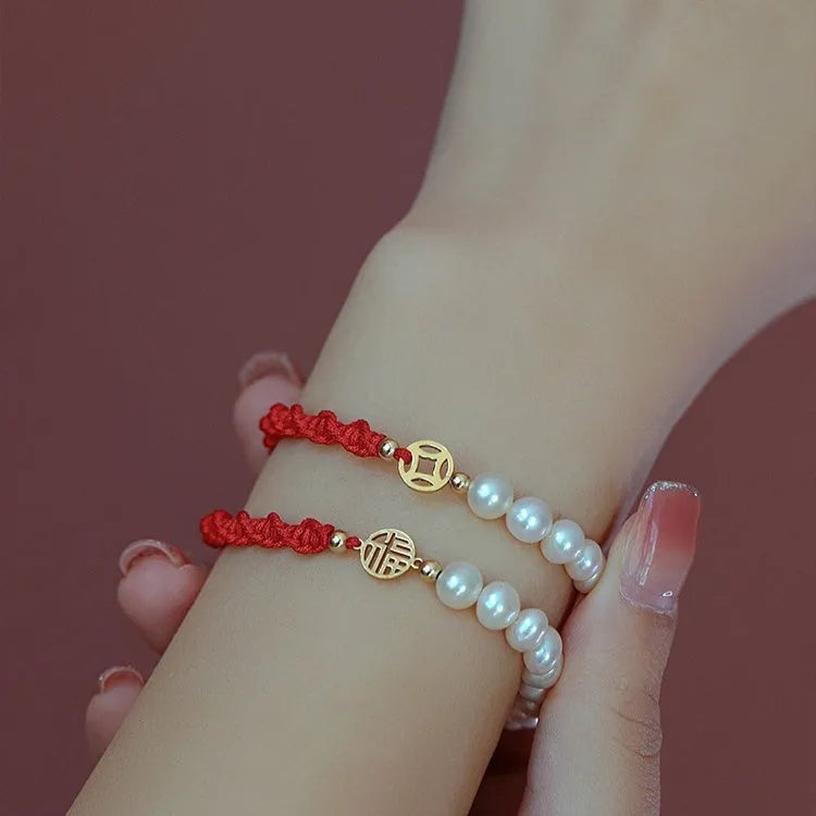 Women's pearl bracelet with braided red rope and gold plated fu character charm