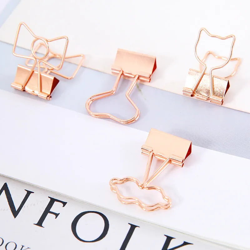 Golden alloy office clip with decorative top, 6.5cm long, holding papers on a desk