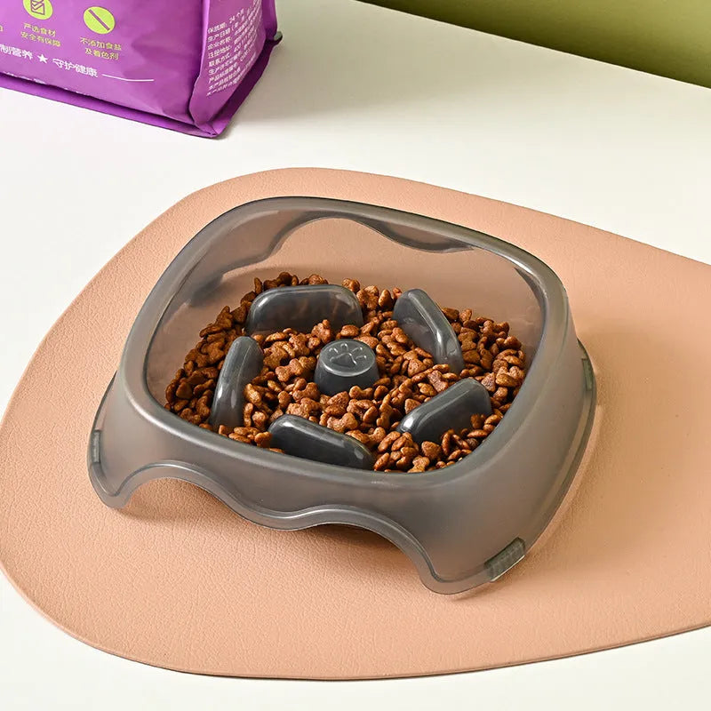 A blue plastic dog slow feeder bowl designed to prevent choking, shown alongside grey, green, and orange colour options.