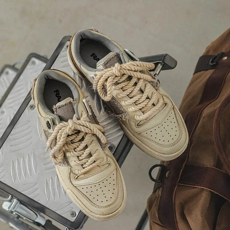 Beige low-top skateboard shoes with microfiber uppers, round toe, and lace-up closure on solid background