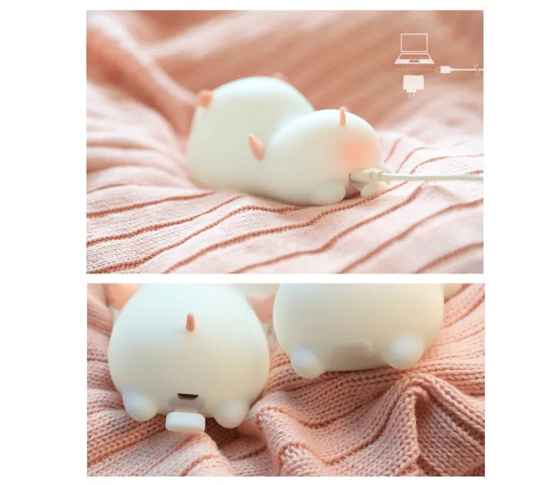 Cute pink silicone pig night light with sleeping design on a bedside table.