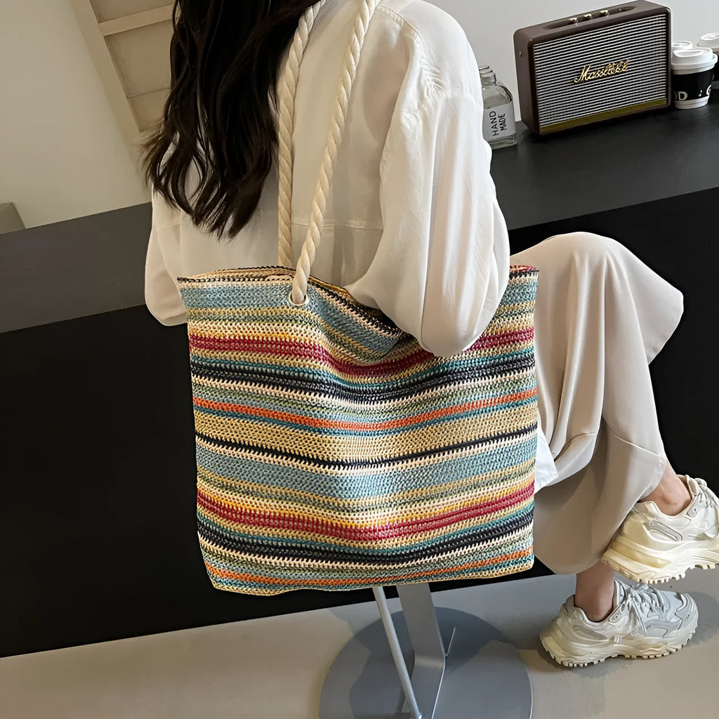 Blue straw woven large capacity shoulder bag with adjustable strap on a neutral background