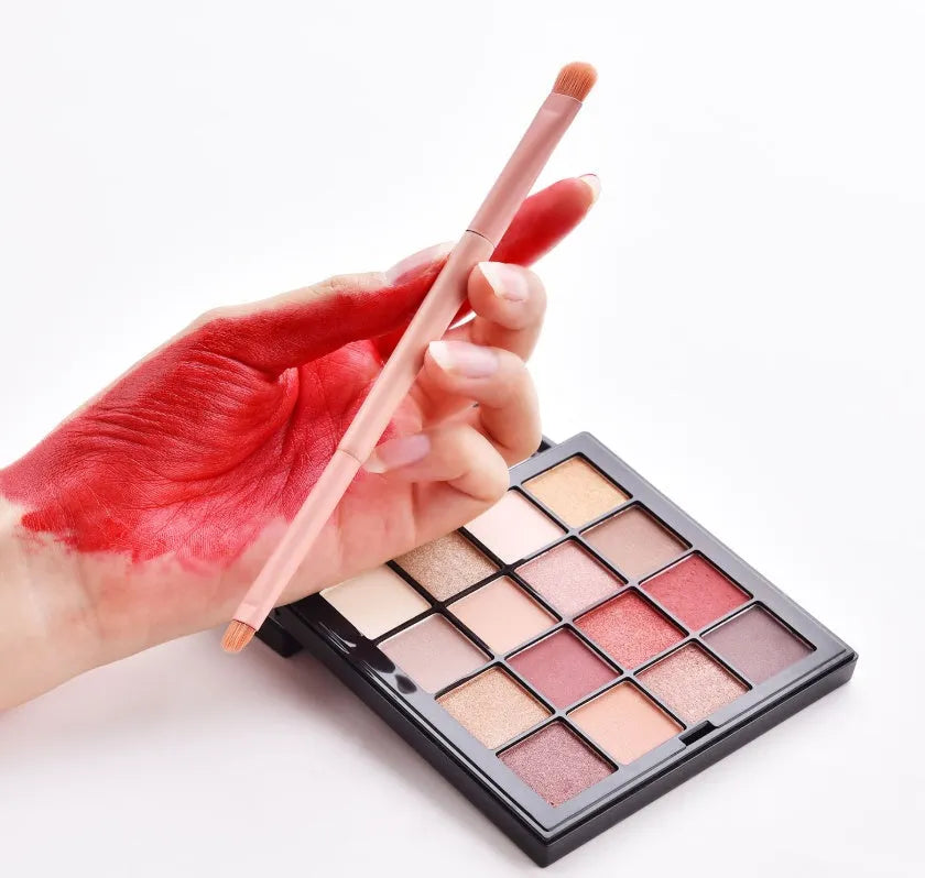 10 cosmetic brushes with wooden handles and nylon bristles arranged with makeup products