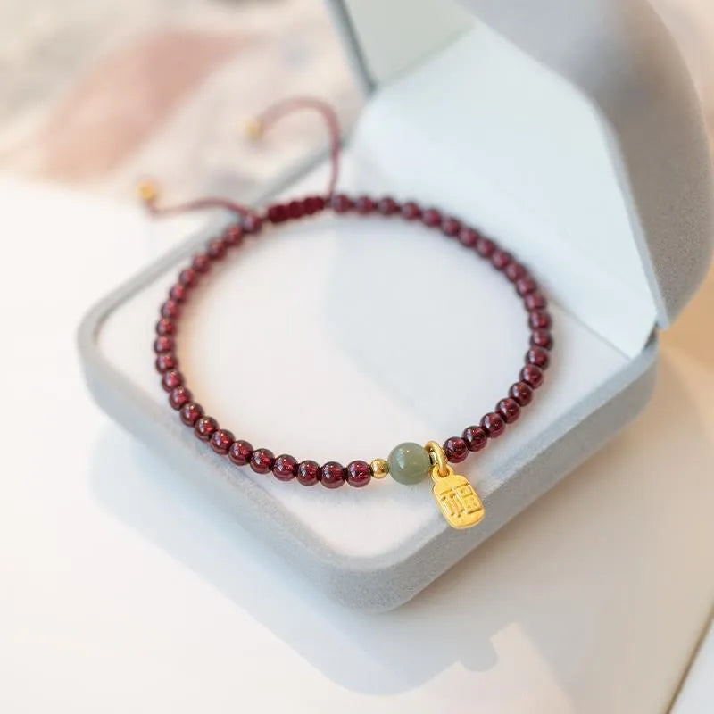 Red rope bracelet with pink strawberry quartz and dark red garnet beads, hand-woven.
