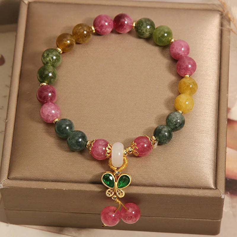 Colourful tourmaline butterfly pendant bracelet with rhinestone details on a woman's wrist.