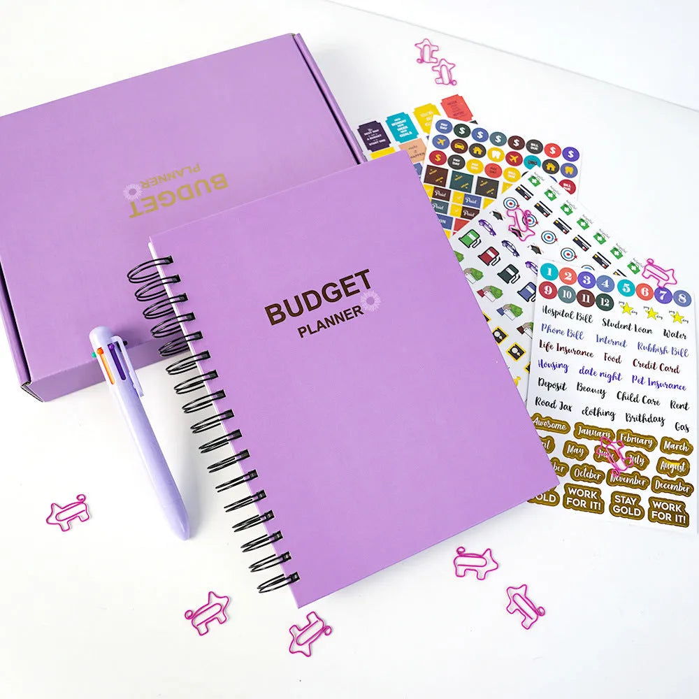 Purple coil-bound financial planning notebook open on a monthly budget page with pen and stickers.