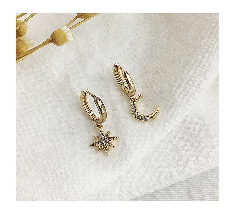 Pair of star moon pendant earrings in copper alloy with crystal detailing, shown in gold and silver options