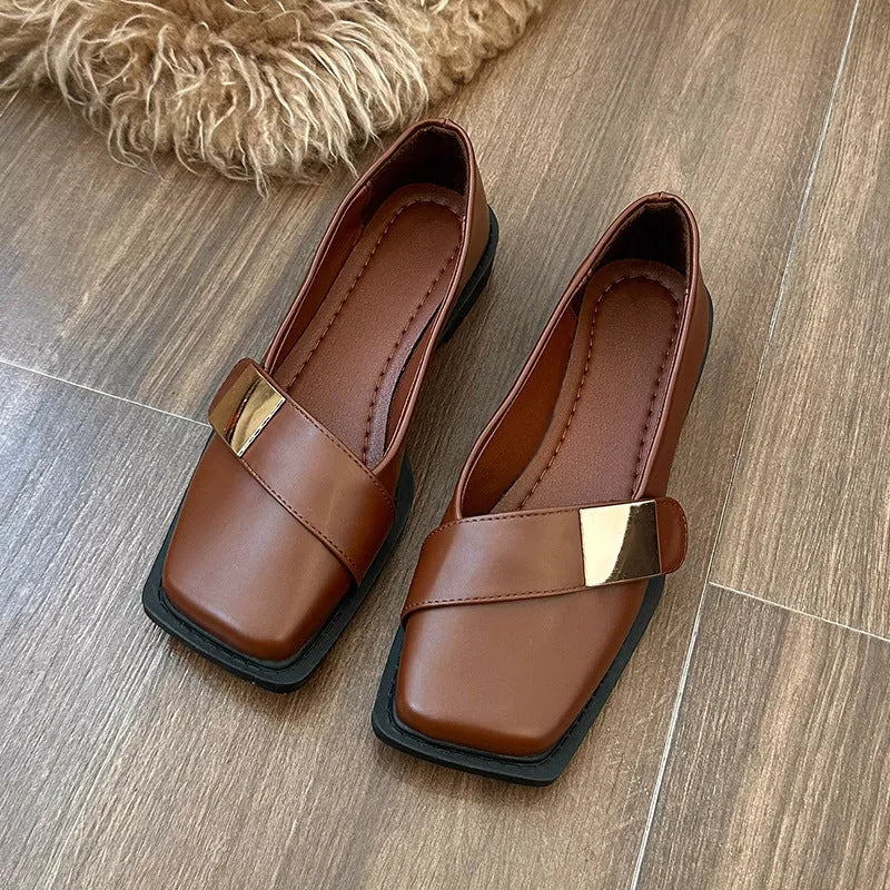 Women's beige square toe flat heel loafers with a silver metal buckle on the upper.