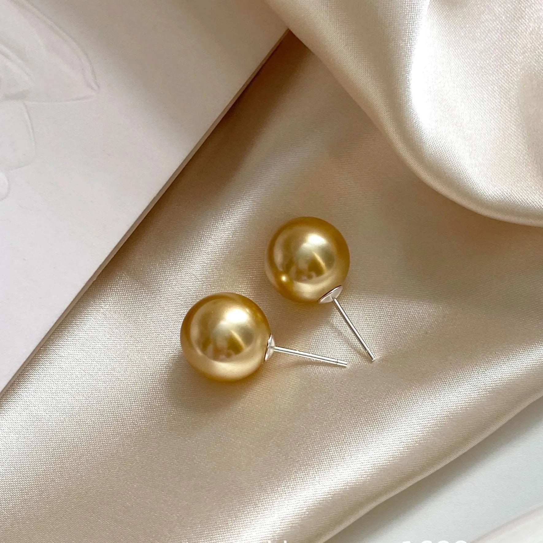 Large pearl stud earrings with geometric eight-point star setting in silver, showing four size options from 8mm to 14mm