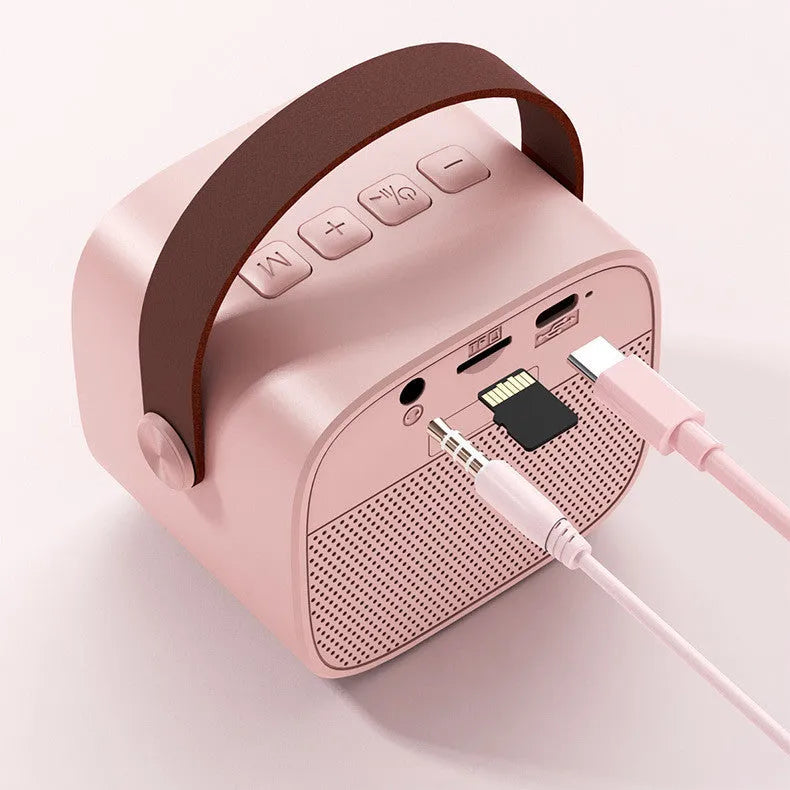 Compact white, pink, or blue portable Bluetooth speaker with USB charging cable.