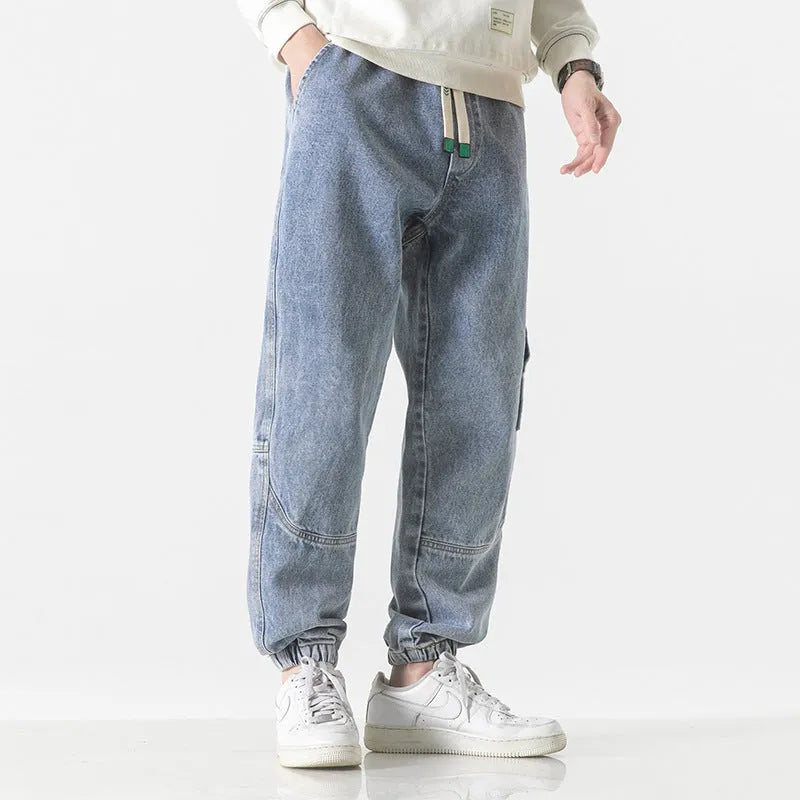 Men's loose-fit tapered trousers in 100% cotton, available in black, blue, and grey colours, showing tapered leg design.