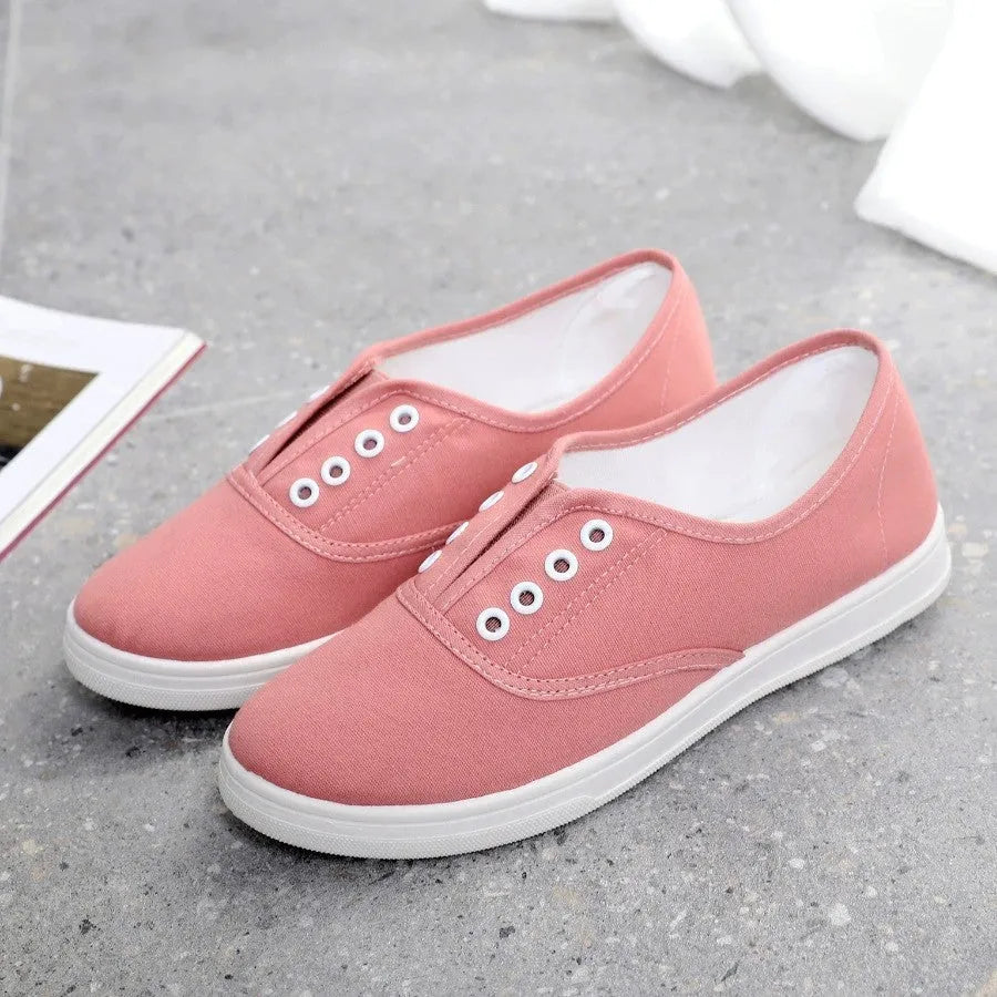 Low-top canvas sneakers in black, white, grey, and pink with a flat heel and cloth lining.